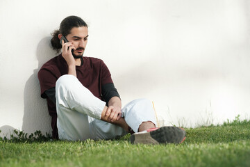Close up portrait of handsome Arab man walking in the park and using smartphone