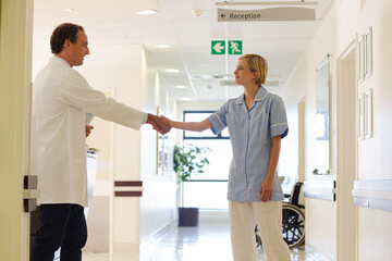 Nurse and doctor shaking hands in hospital