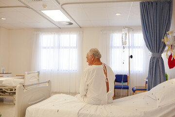 Older patient wearing gown in hospital room