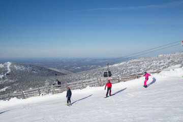 Fototapeta na wymiar The ski slopes of the resort. Skiers and snowboarders on the slope of the ski resort