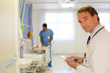 Obraz premium Doctor reading clipboard in hospital room
