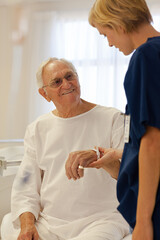 Obraz premium Nurse reading older patient's medical bracelet in hospital