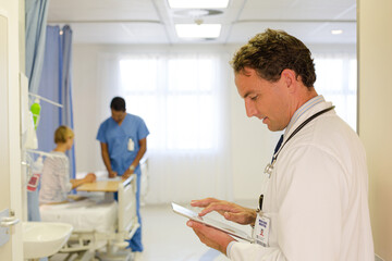 Fototapeta premium Doctor reading clipboard in hospital room