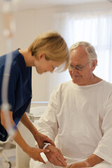 Obraz premium Nurse reading older patient's medical bracelet in hospital