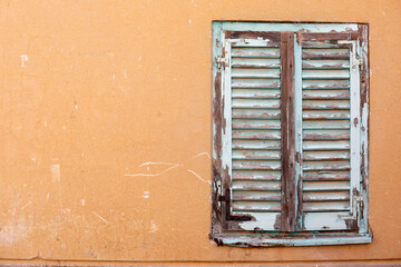 Old white window with wooden shutters on a wall.