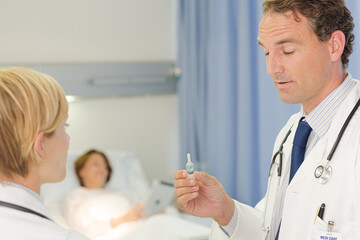 Obraz premium Doctor checking syringe in hospital room