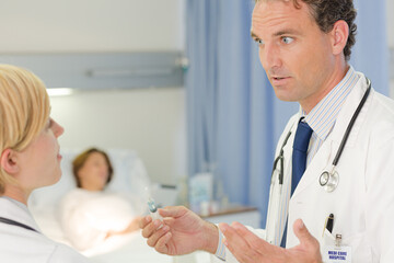 Obraz premium Doctor checking syringe in hospital room