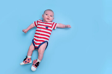 A newborn baby dressed in the colors of the American flag of the United States, blue studio background. A child in the clothes of the red and white USA flag