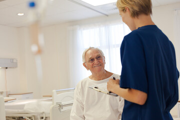 Obraz premium Nurse and older patient talking in hospital room