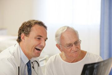 Doctor showing x-rays to older patient in hospital room