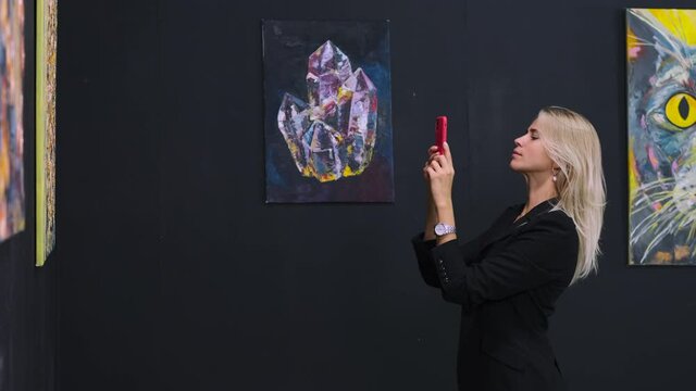 woman is photographing artworks in museum with pictures of modern artist