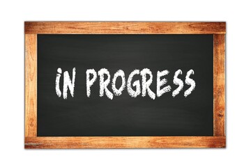 IN  PROGRESS text written on wooden frame school blackboard.