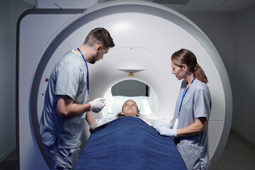 Two young radiologists in uniform consulting little girl before mri scan examination
