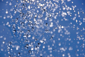 Water drops flying in the air on a blue background.