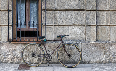 Fototapeta na wymiar vintage bicycle in poor condition tied to a window grille of a house in a historic district, copy space