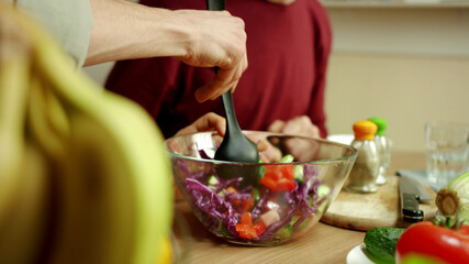 Two men are pouring the sauce over the salad and sterring it © iaginzburg