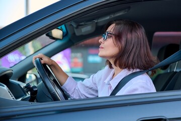 Fototapeta na wymiar Middle-aged beautiful woman driver driving a car