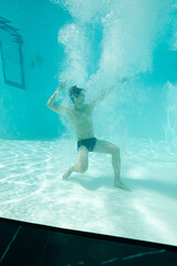 Man posing underwater in swimming pool