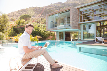 Man using laptop at poolside