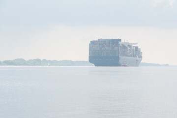 Obraz premium Cargo container ship departing from the port to the sea in the mist