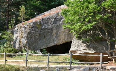 Large rock cave at the entrance to the Black Lagoon. Cobbled road with wooden railing, Soria province, Spain.