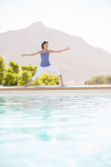 Woman practicing yoga at poolside