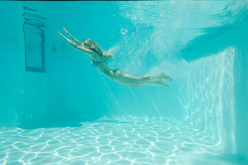 Woman swimming underwater in pool