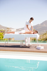 Woman receiving massage poolside at spa