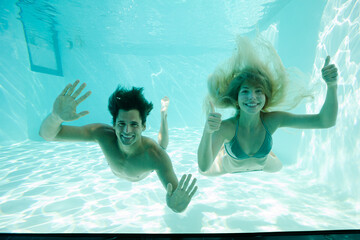 Smiling couple underwater in pool - Powered by Adobe