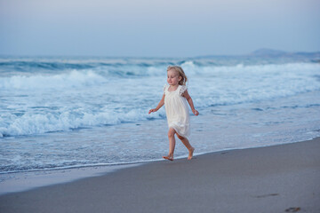 Fototapeta na wymiar Happy little girl running and jumping at beach
