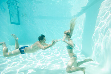 Couple swimming underwater in pool