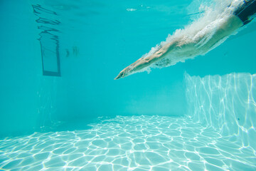 Man swimming underwater in pool