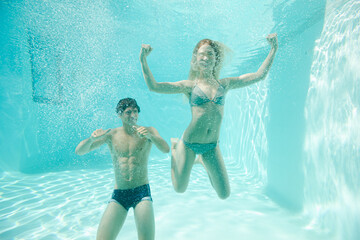 Obraz na płótnie Canvas Couple posing underwater in swimming pool