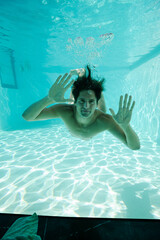 Obraz na płótnie Canvas Man looking through window underwater in swimming pool