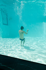 Obraz na płótnie Canvas Man posing underwater in swimming pool