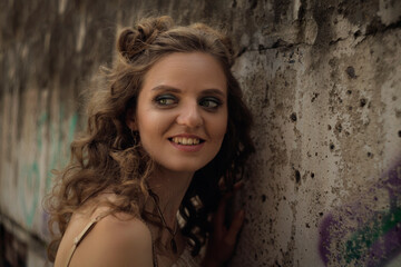 Naklejka premium Young beautiful curly-haired girl stands by the wall