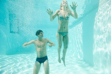 Couple posing underwater in swimming pool