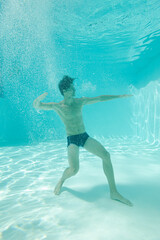 Man posing underwater in swimming pool