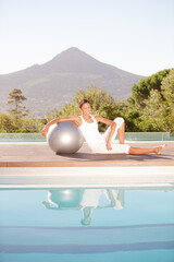 Woman stretching over fitness ball at poolside