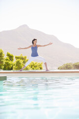 Woman practicing yoga at poolside