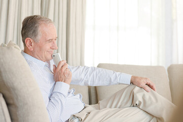 Older man using cell phone on sofa