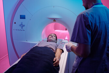 Young female patient looking at radiographer before medical diagnostics in mri scan machine