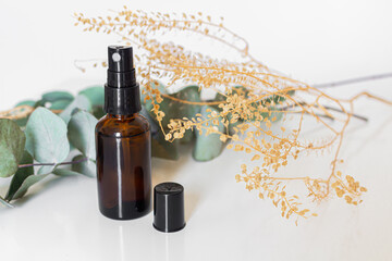 Brown glass sprinkler and dry eucalyptus branches on white background.