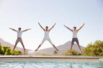 People jumping with arms and legs outstretched at poolside