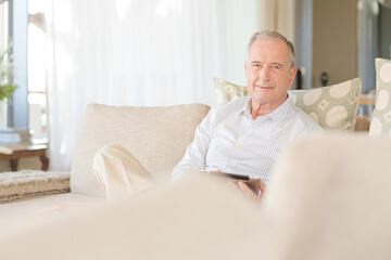 Older man reading newspaper on sofa