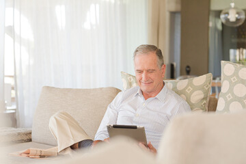 Man using tablet computer on sofa