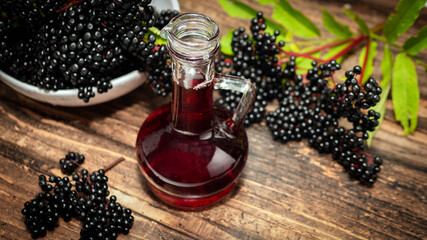 Ripe elderberry on a wooden background, tincture of herbs from black berries in a bottle.Medicine...