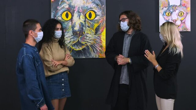 people with face masks are viewing exhibition with guide in fine art gallery