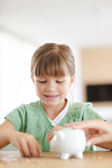 Girl filling piggy bank on counter