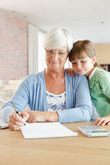 Older woman and granddaughter using calculator